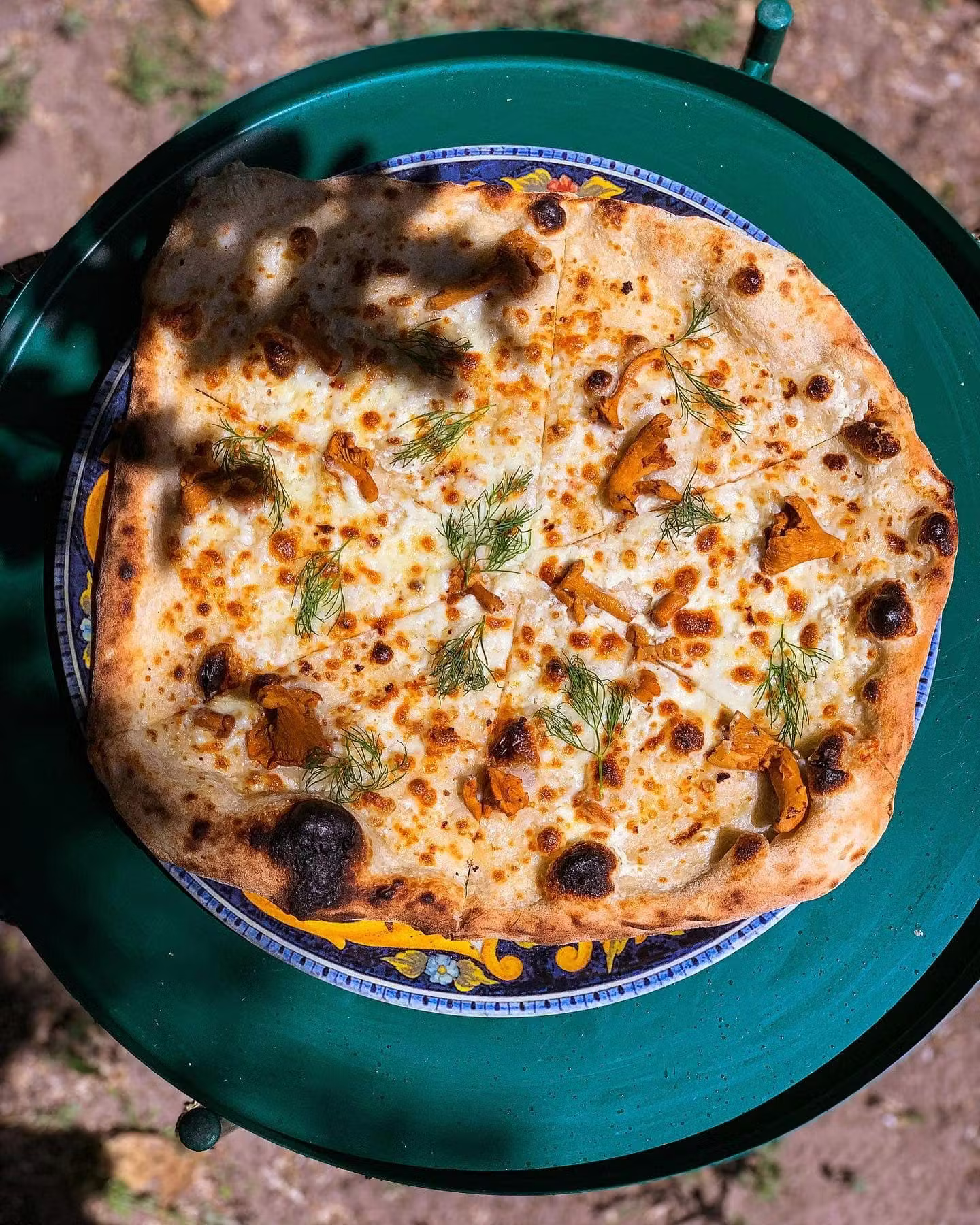 Biała pizza z kurkami i koperkiem na ceramicznym talerzu