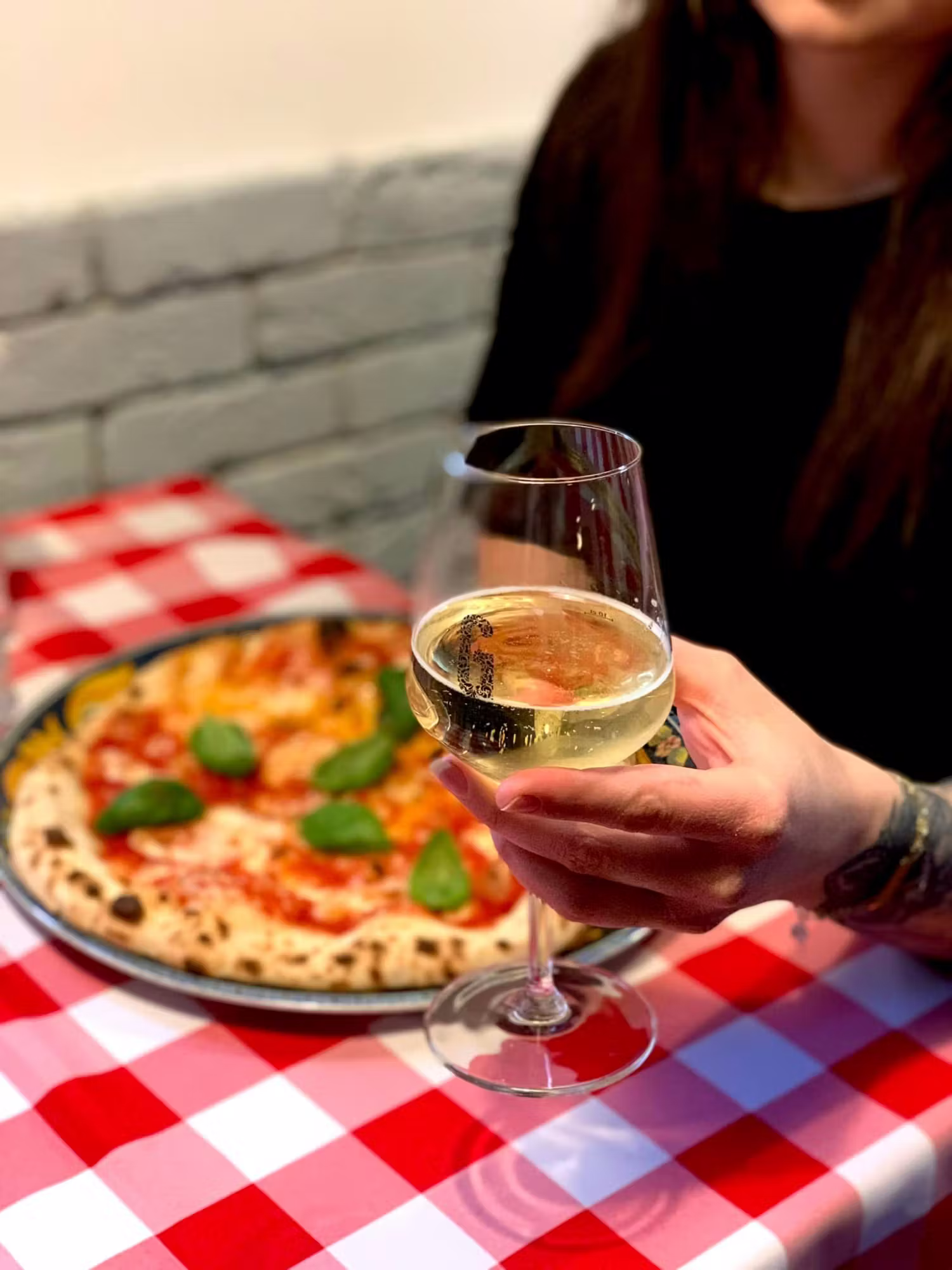 Pizza Margherita i lampka białego wina na obrusie w kratkę